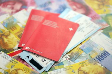 İsviçre frangı banknotları ve biletli pasaport. Mevcut banknotlar ve biyometrik geçiş kartları büyük miktarda masada yatıyor. İsviçre 'de seyahat ve tatil kavramı