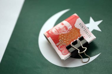 Pakistan bayrağı üzerinde Pakistan banknotları. Pakistan 'ın mevcut para faturaları büyük miktarlarda pankartta yatıyor. Pakistan 'da ekonomi ve ticaret kavramı