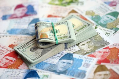 Amerikan dolarları yığını Pakistan Rupi banknotlarının büyük bir miktarına yakın duruyor. Amerikan para demeti Pakistan 'ın para banknotlarında yatıyor. Pakistan 'da ekonomi ve döviz kuru kavramı