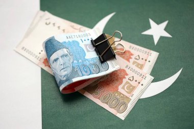 Pakistan bayrağı üzerinde Pakistan banknotları. Pakistan 'ın mevcut para faturaları büyük miktarlarda pankartta yatıyor. Pakistan 'da ekonomi ve ticaret kavramı