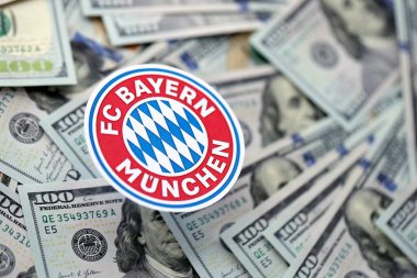 KYIV, UKRAINE - 23 Şubat 2025 Bayern Münih futbol kulübü rozeti 100 dolarlık banknotların üzerinde yatıyor