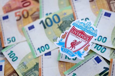 KYIV, UKRAINE - 23 Şubat 2025 Liverpool UK FC futbol kulübü rozeti büyük miktarda EURO para banknotları üzerine kuruludur