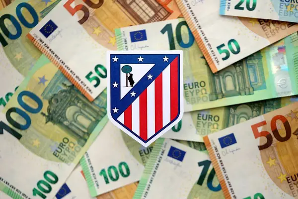 KYIV, UKRAINE - 23 Şubat 2025 Atletico de Madrid futbol kulübü rozeti büyük miktarda EURO para banknotlarının üzerinde yatıyor
