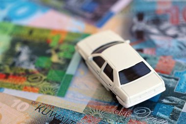 Kuveyt dinarı para ve oyuncak araba faturaları. Araba sahibi olma kavramı.