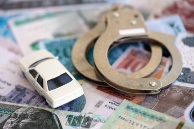 Mısır para birimi banknotları ve kelepçeli oyuncak araba. Araba kazası kavramı.