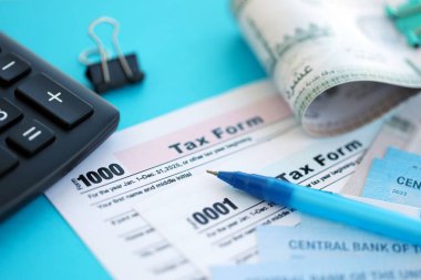 Birleşik Arap Emirlikleri kara para faturaları ve mavi üzerine yakın vergi formlu hesap makinesi. Vergi ve muhasebe kavramı