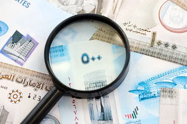 Birleşik Arap Emirlikleri kara para birimi banknotları ve büyüteç yakın çekim. Finansal izleme ve vergilendirme kavramı