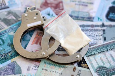 Mısır para birimi banknotları ve kelepçeli kokain paketi. Uyuşturucu suçları kavramı