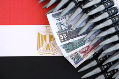 Mısır para birimi banknotları ve bayraklar üzerinde tüfek mermileri. Savaş ve silah satışı kavramı
