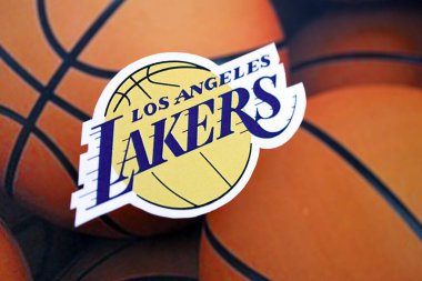 KYIV, UKRAINE - 23 Şubat 2025 Los Angeles Lakers basketbol takımı rozeti basketbol topu arka plan pankartında yatıyor