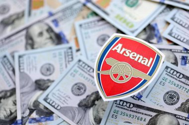 KYIV, UKRAINE - 23 Şubat 2025 Arsenal FC futbol kulübü rozeti yüzlük banknotların üzerinde yatıyor