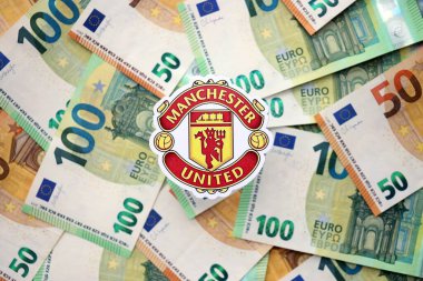 KYIV, UKRAINE - 23 Şubat 2025 Manchester United FC futbol kulübü rozeti büyük miktarda EURO para banknotlarının üzerinde yatıyor