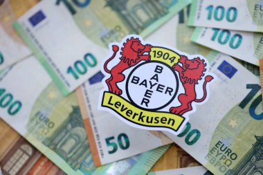 KYIV, UKRAINE - 23 Şubat 2025 Bayer 04 Leverkusen futbol kulübü rozeti büyük miktarda EURO para banknotları üzerinde yatıyor