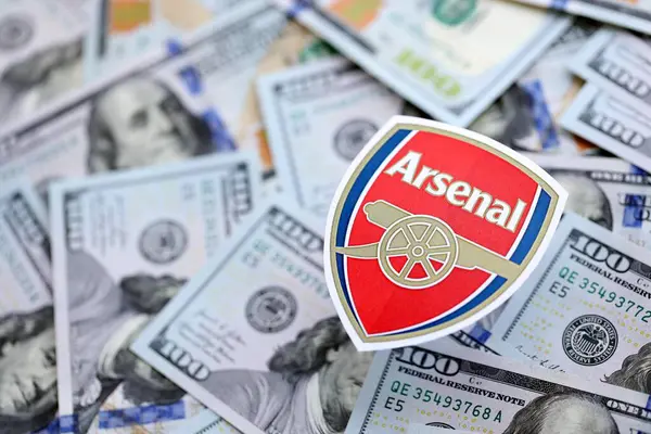KYIV, UKRAINE - 23 Şubat 2025 Arsenal FC futbol kulübü rozeti yüzlük banknotların üzerinde yatıyor
