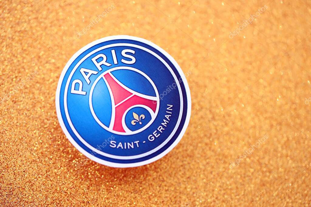 KYIV, UKRAINE - FEBRUARY 23, 2025 Paris Saint Germain FC football club badge lies on golden yellow glitter background banner
