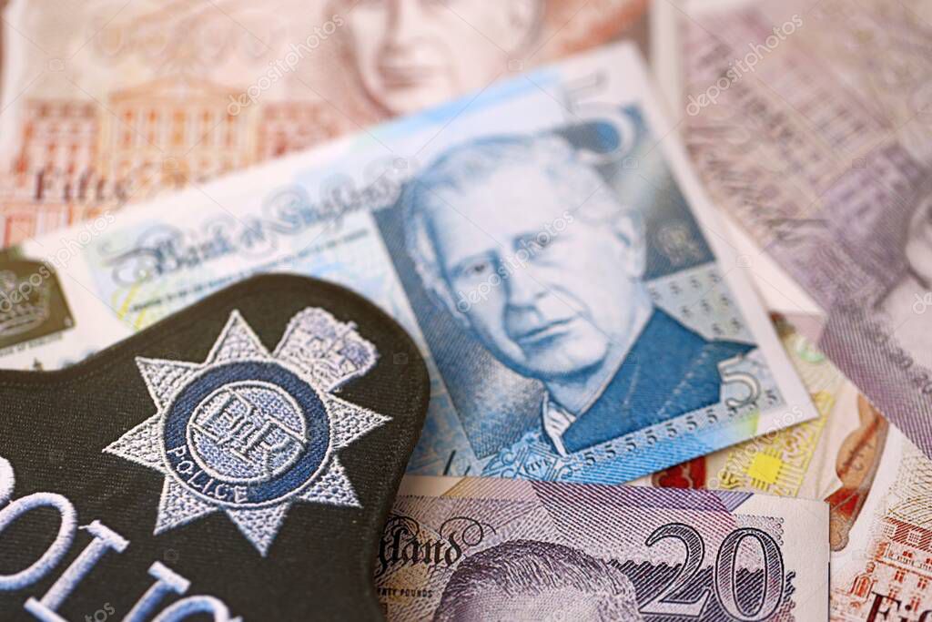KYIV, UKRAINE - SEPTEMBER 17, 2025 United Kingdom Police badge on British pound money bills close up