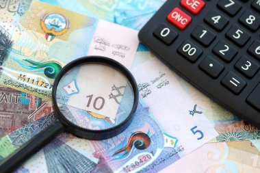 Kuveyt para birimi faturaları ve büyüteçle yakın çekim yapan hesap makinesi. Vergilendirme ve para sayımı kavramı