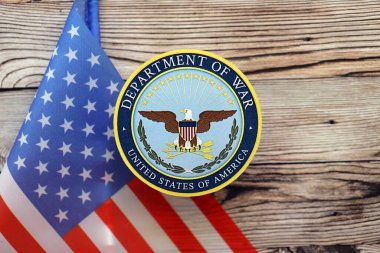 KYIV, UKRAINE - 17 Eylül 2025 ABD Savaş Bakanlığı rozeti ve ahşap masa üzerinde bayrak