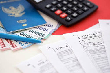 KYIV, UKRAINE - JANUARY 27, 2024 Indonesian tax forms 1770 Individual Income Tax Return and passport with pen on table close up