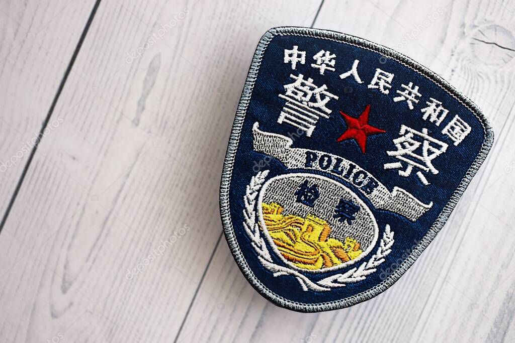 KYIV, UKRAINE - SEPTEMBER 17, 2025 Chinese Police badge on white wooden table surface close up
