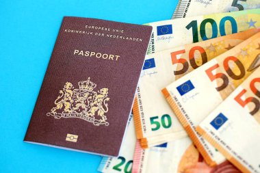 Hollanda pasaportu, mavi arka planda Avro para banknotlarıyla birlikte yakın planda bulunuyor. Avrupa 'da maaş ve emeklilik kavramı