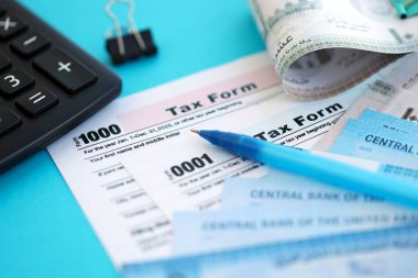 Birleşik Arap Emirlikleri kara para faturaları ve mavi üzerine yakın vergi formlu hesap makinesi. Vergi ve muhasebe kavramı