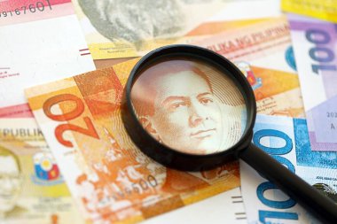 Filipinler Peso para birimi faturaları ve büyüteç yakın çekim. Finansal izleme ve vergilendirme kavramı