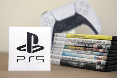 KYIV, UKRAINE - 17 Eylül 2025 PS5 video oyun diski kutuları ve modern dualsense kenar oyun sahası. Ön tarafta PS5 logosu var.