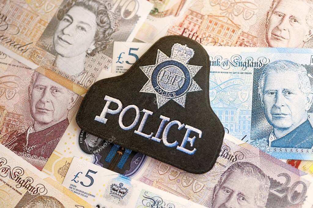 KYIV, UKRAINE - SEPTEMBER 17, 2025 United Kingdom Police badge on British pound money bills close up