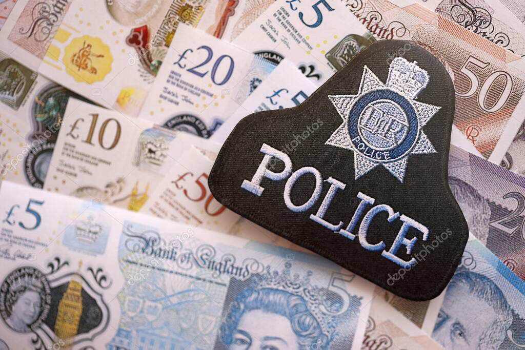 KYIV, UKRAINE - SEPTEMBER 17, 2025 United Kingdom Police badge on British pound money bills close up