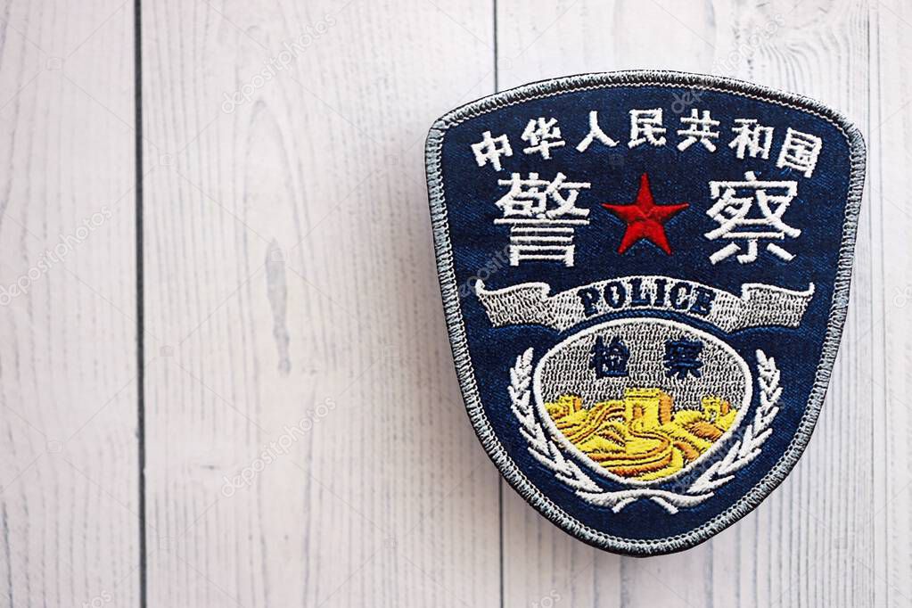 KYIV, UKRAINE - SEPTEMBER 17, 2025 Chinese Police badge on white wooden table surface close up