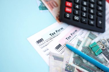 Egyptian pound money bills and calculator with tax form close up on blue. Taxation and accounting concept