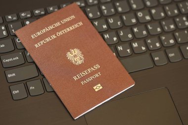 Avusturya pasaportu siyah dizüstü bilgisayarın klavye tuşlarının üzerinde duruyor. Avrupa konseptinde teknoloji ve kontrol