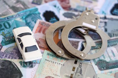Mısır para birimi banknotları ve kelepçeli oyuncak araba. Araba kazası kavramı.