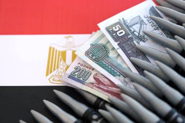Mısır para birimi banknotları ve bayraklar üzerinde tüfek mermileri. Savaş ve silah satışı kavramı