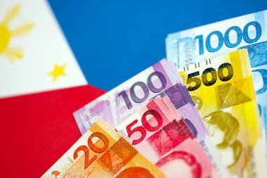 Filipinler Peso para birimi banknotları bayrağın üzerinde duruyor. İş ve yatırım kavramı