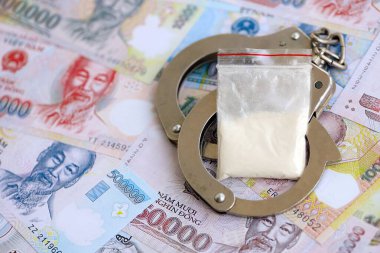 Vietnam dong para birimi faturaları ve kelepçeli kokain paketi. Uyuşturucu suçları kavramı