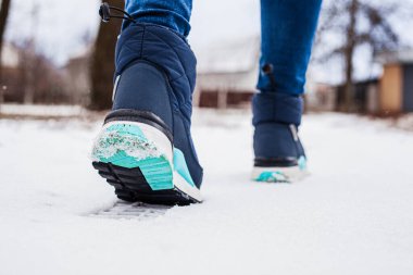 Winter puffy boots on female legs in winter on snow