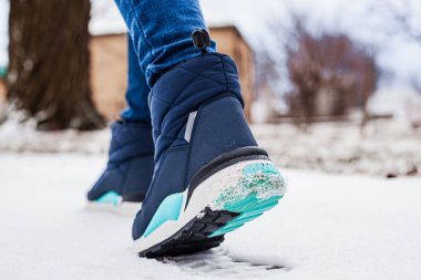 Winter puffy boots on female legs in winter on snow