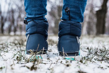 Winter puffy boots on female legs in winter on snow