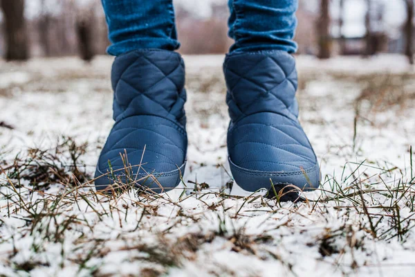 Winter puffy boots on female legs in winter on snow