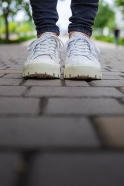 Siyah kotlu kadın bacaklarında çivili tabanlı beyaz spor ayakkabılar.