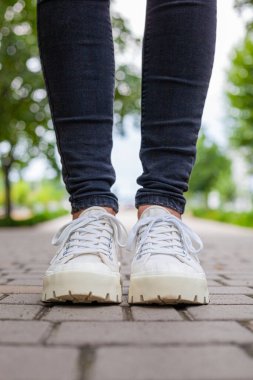 Siyah kotlu kadın bacaklarında çivili tabanlı beyaz spor ayakkabılar.