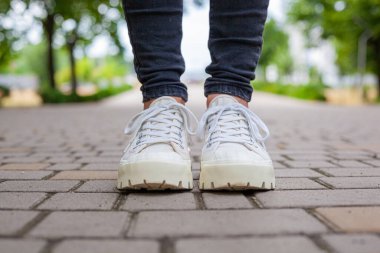 Siyah kotlu kadın bacaklarında çivili tabanlı beyaz spor ayakkabılar.