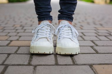 Siyah kotlu kadın bacaklarında çivili tabanlı beyaz spor ayakkabılar.