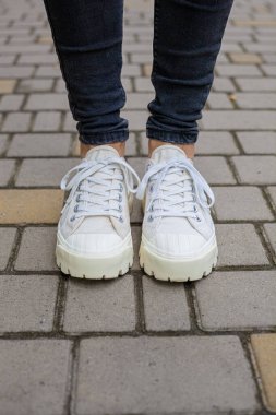 Siyah kotlu kadın bacaklarında çivili tabanlı beyaz spor ayakkabılar.
