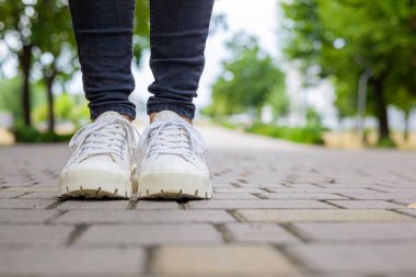 Siyah kotlu kadın bacaklarında çivili tabanlı beyaz spor ayakkabılar.
