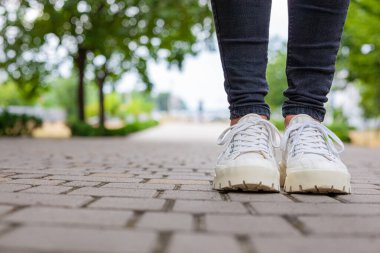 Siyah kotlu kadın bacaklarında çivili tabanlı beyaz spor ayakkabılar.
