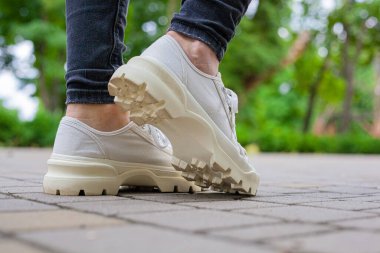 Siyah kotlu kadın bacaklarında çivili tabanlı beyaz spor ayakkabılar.