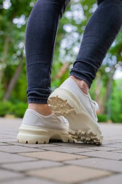Siyah kotlu kadın bacaklarında çivili tabanlı beyaz spor ayakkabılar.